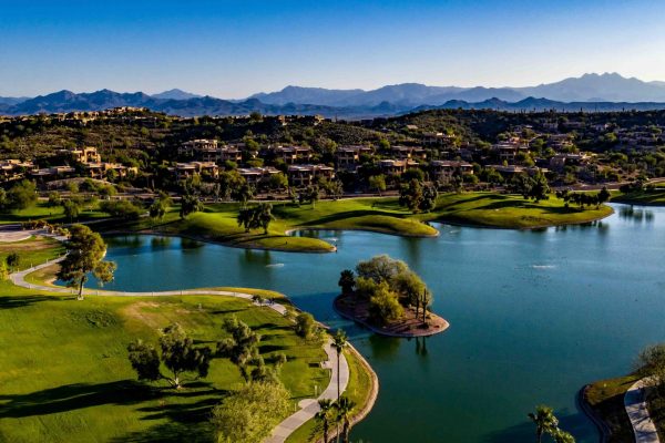 Aerial, drone, panoramic view over Fountain Hills Lake in Fountain Hills, Arizona with beautiful landscaped park area, clear, blue water and sky